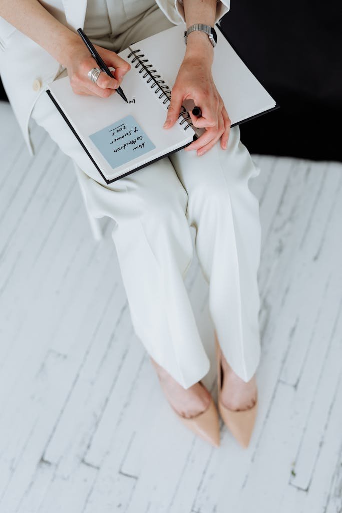 Close-up of a woman writing in a notepad while seated indoors.
